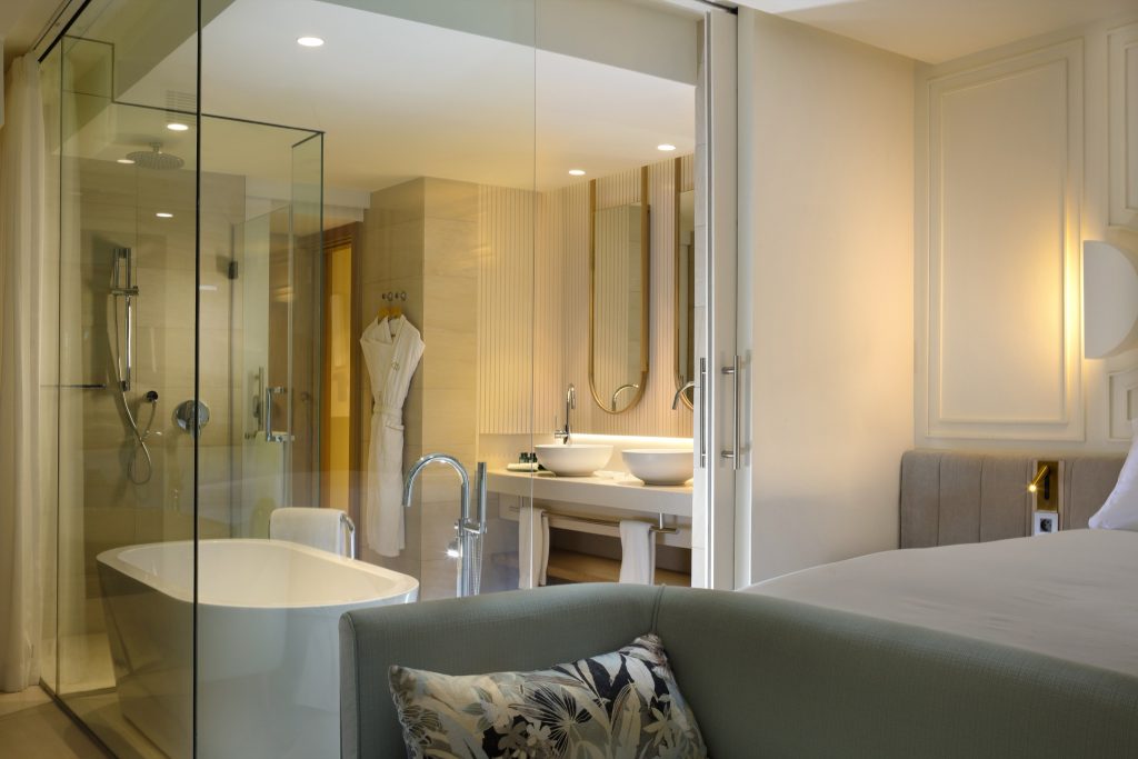 Modernes Badezimmer mit Glaswand, freistehender Badewanne, Dusche und Doppelwaschbecken im Magnifique Room