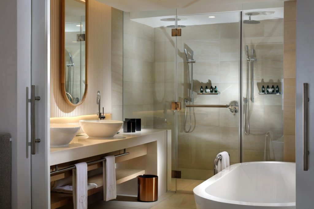 Badezimmer der Opera Suite mit zwei ovalen Waschbecken, Glasduschwand und freistehender Badewanne
