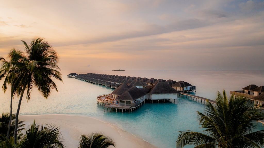Restaurant Roma im Sun Siyam Iru Veli mit Strohdach-Bungalows auf Stegen über türkisfarbenem Wasser und Palmen am Ufer