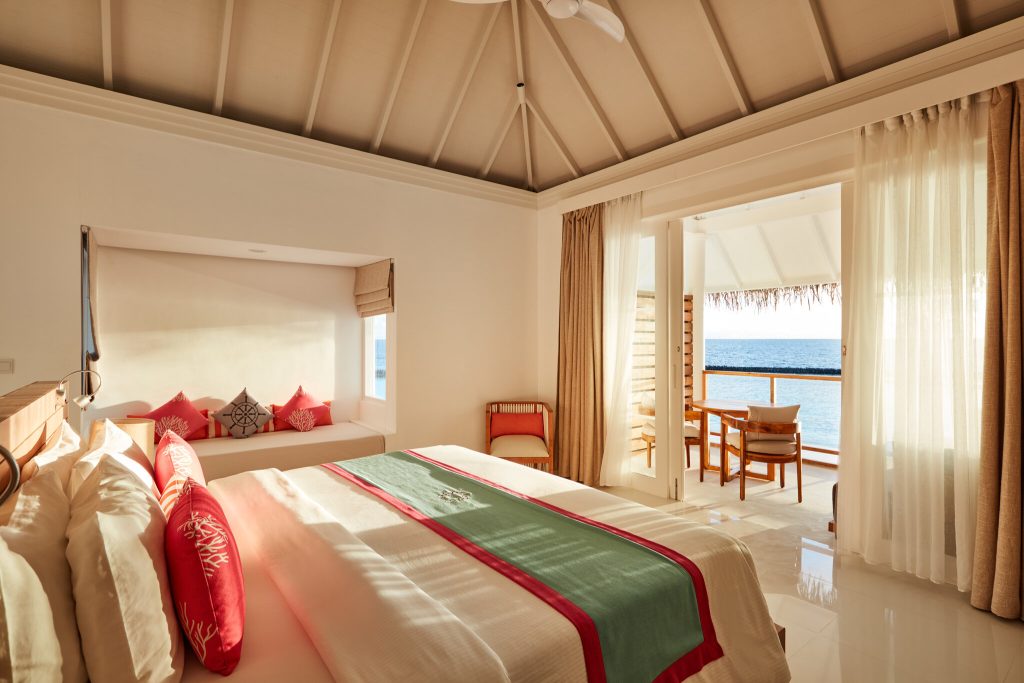 Zimmer der Beach Residence mit großem Bett, Holzmöbeln, Terrasse und Meerblick bei Tageslicht