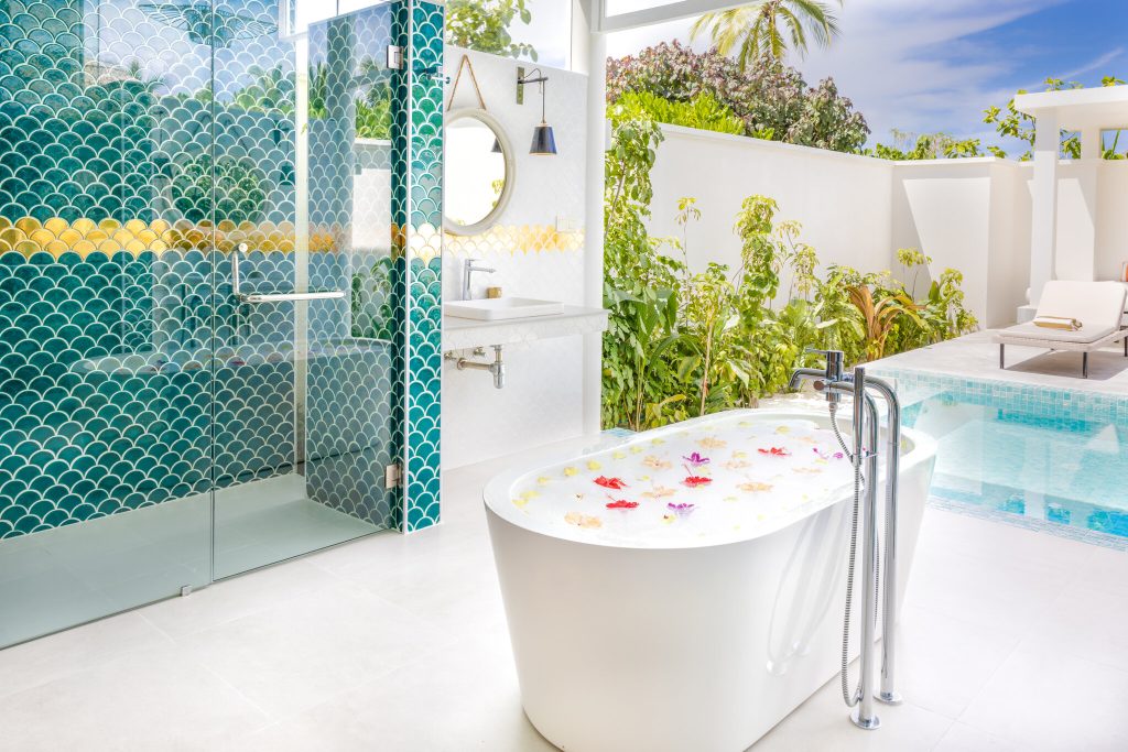 Outdoor-Badebereich der Grand Beach Villa mit freistehender weißer Badewanne und türkisfarbener Duschkabine