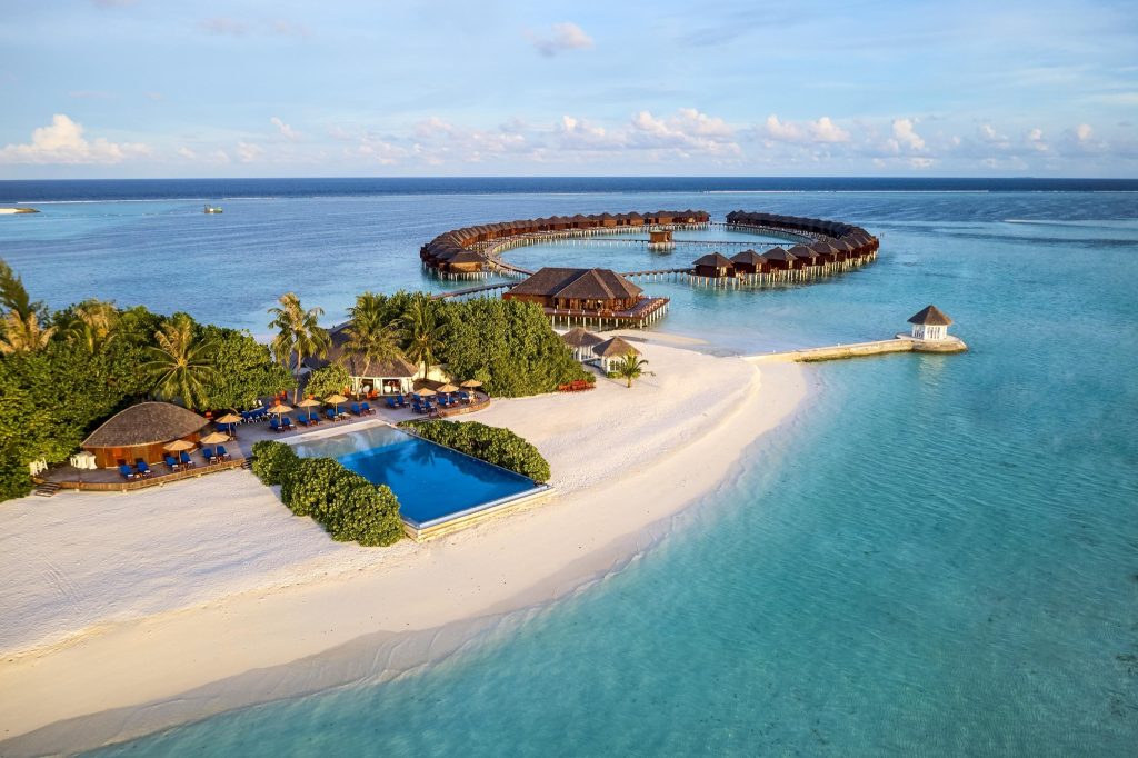 Luftaufnahme des Infinity-Pools mit Liegen, Palmwedeldächern und weißem Sandstrand im Sun Siyam Olhuveli
