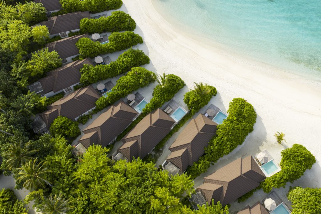 Mehrere Grand Beach Villas mit braunen Dächern, privaten Pools und Liegestühlen am weißen Sandstrand