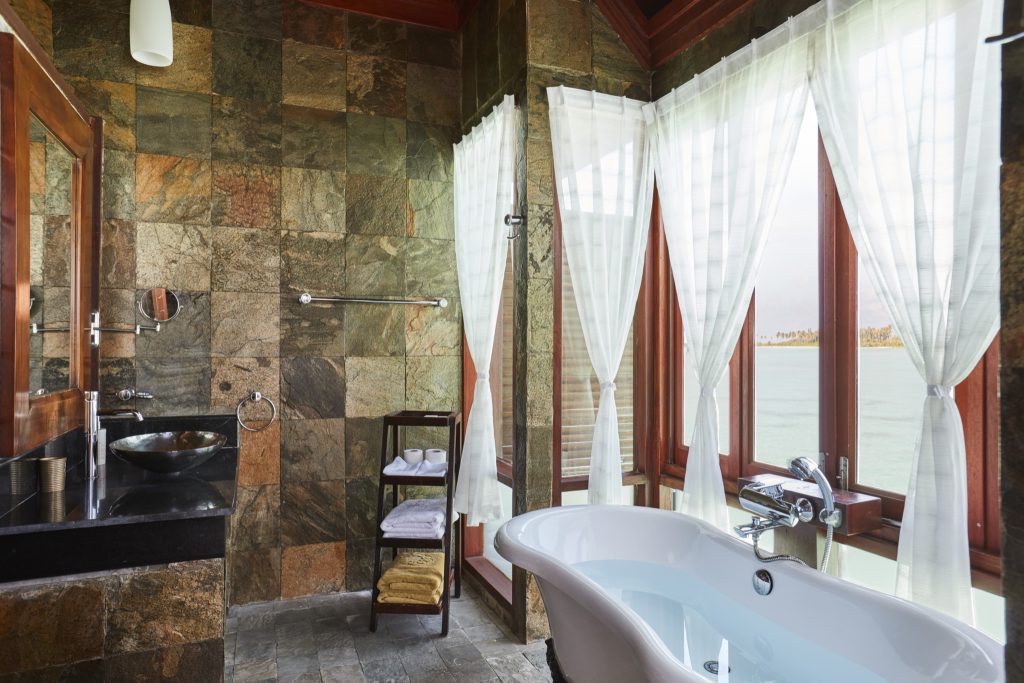 Badezimmer mit freistehender Badewanne, Natursteinfliesen, dunklem Holzwaschtisch und Meerblick in der Prestige Jacuzzi.