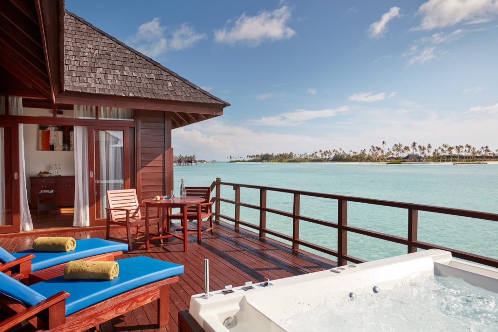 Außenterrasse der Prestige Jacuzzi Water Villa mit Holz, zwei blauen Liegestühlen, Whirlpool und Meerblick auf den