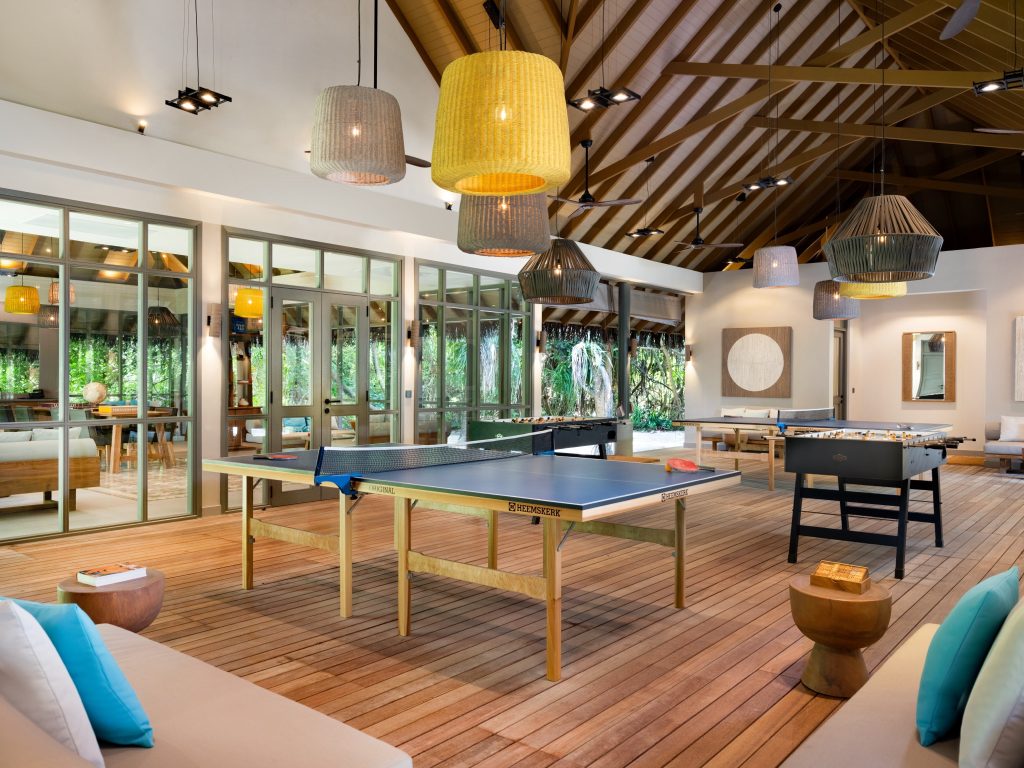 Freizeitraum im Vakkaru Maldives mit Tischtennistisch, Tischfußball, Holzboden und großen Glaswänden