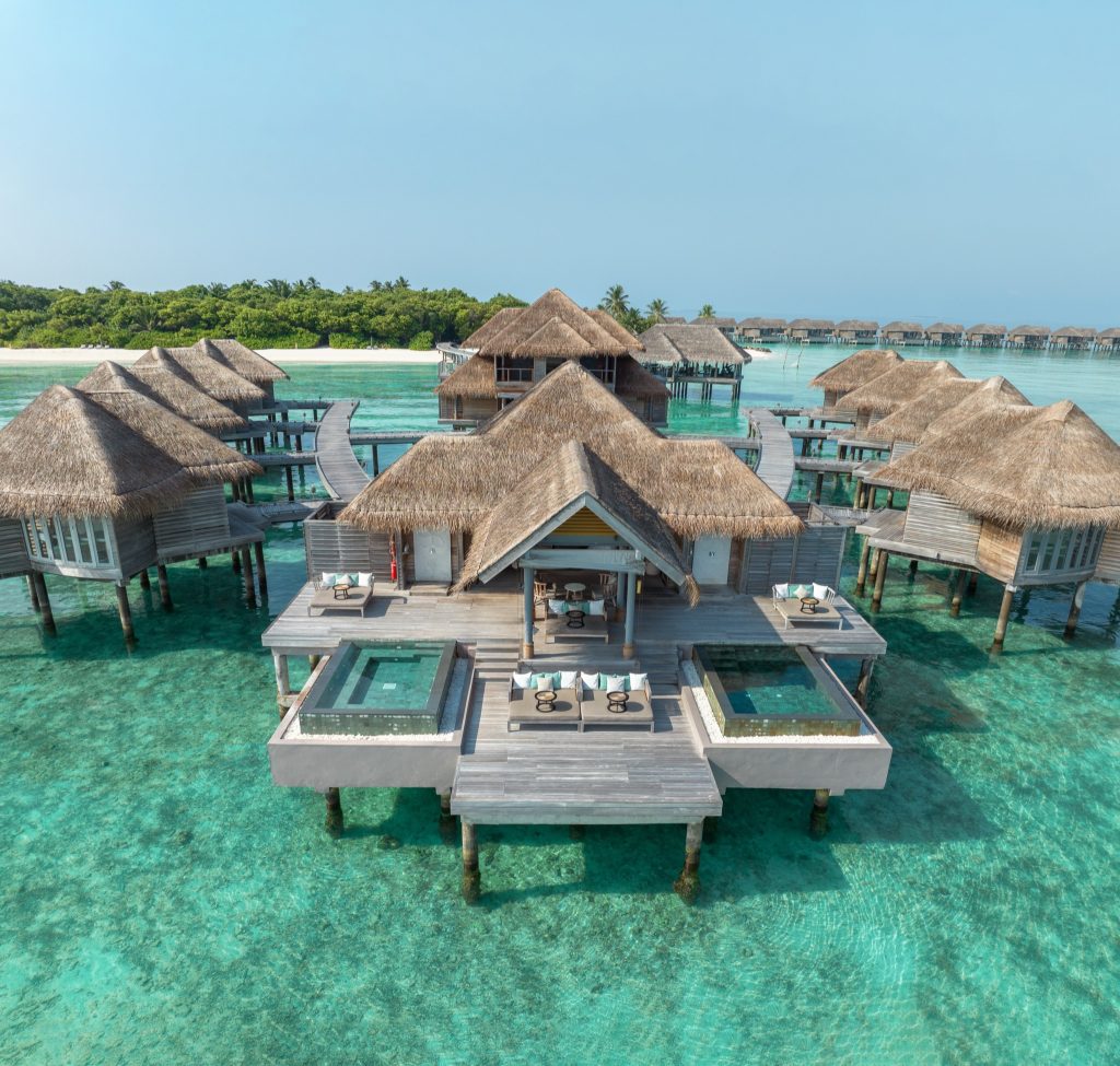 Wasserbungalows mit Strohdächern auf Stelzen über klarem türkisblauem Wasser im Vakkaru Maldives Resort