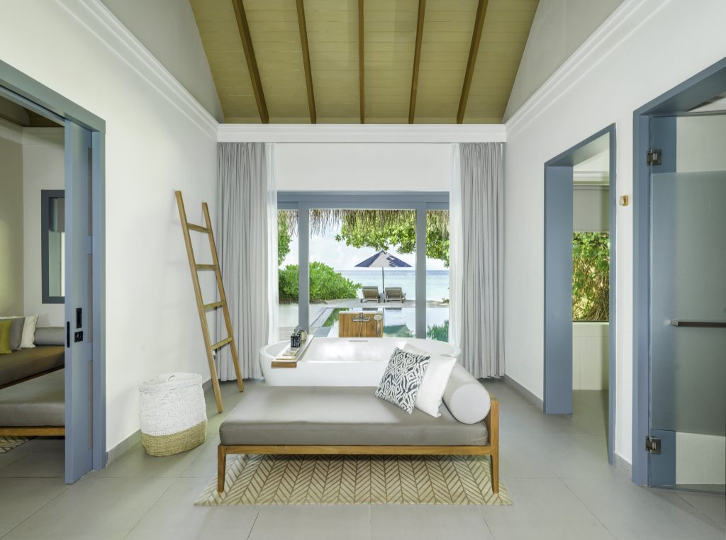 Hotelzimmer mit Chaiselongue, großem Fenster, Blick auf Pool und Meer im Vakkaru Maldives