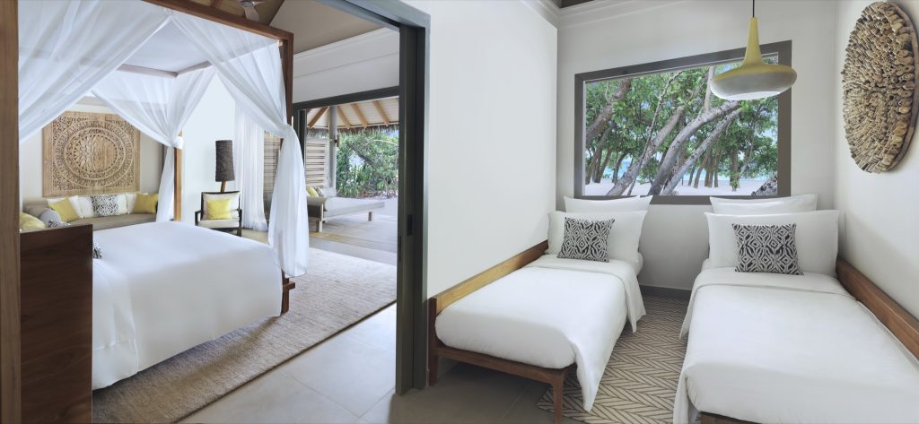 Zwei verbundene Hotelzimmer mit Himmelbett, Einzelbetten, Holzmöbeln und Blick auf Strand