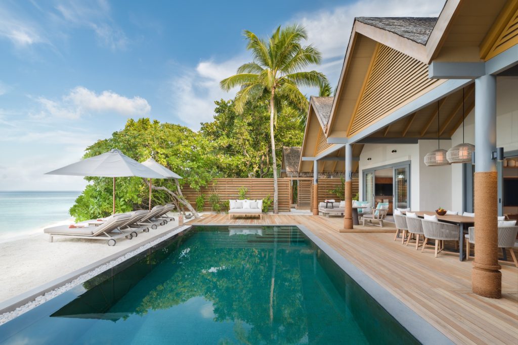 Terrasse der Three Bedroom Beach Pool Residence mit Pool, Sonnenliegen, Esstisch und direktem Strandzugang auf den