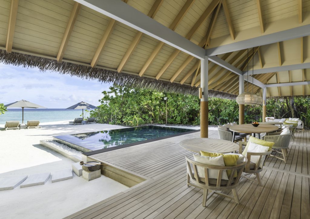 Offene Terrasse der Two Bedroom Beach Pool Residence mit Holzdeck, Sitzgruppe, Pool und Blick auf Strand und Meer