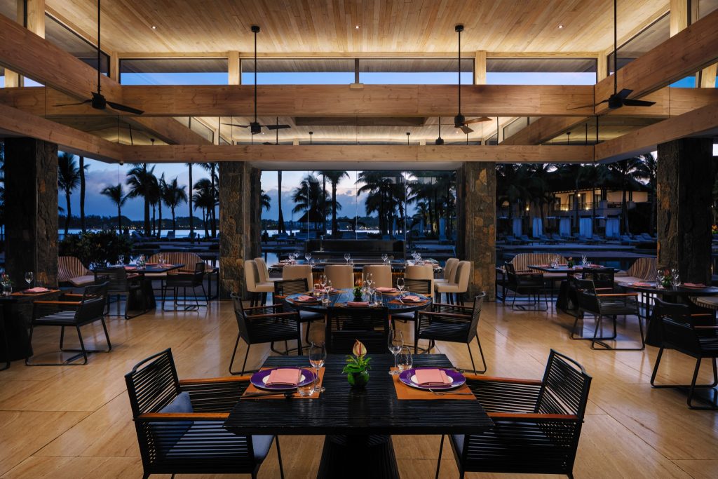 Innenansicht des Restaurant Fusion im The Westin Turtle Bay Resort & Spa Mauritius mit Holz, Stein und Glas bei Dämmerung