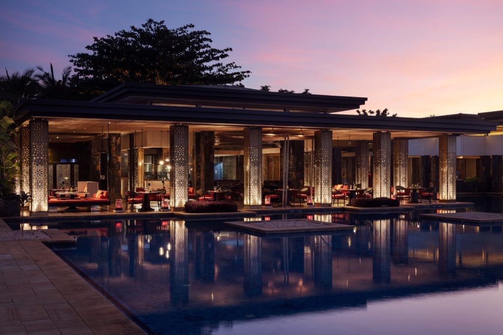 Restaurant Kangan im The Westin Turtle Bay Resort & Spa Mauritius mit beleuchteten Säulen und Swimmingpool bei Abenddämmerung
