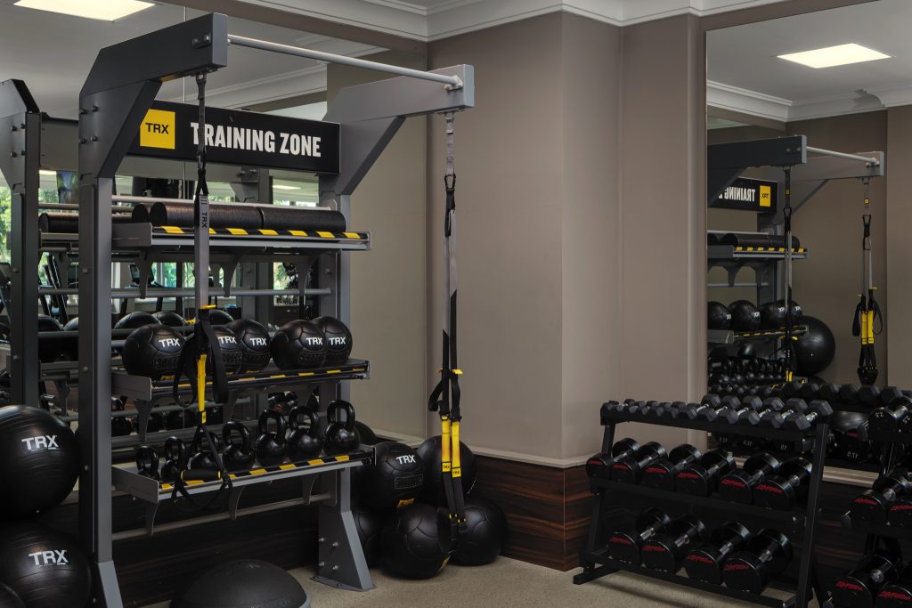 Moderner Fitnessraum mit TRX, Medizinbällen, Kettlebells und Hantelständer in Schwarz, Grau und Gelb