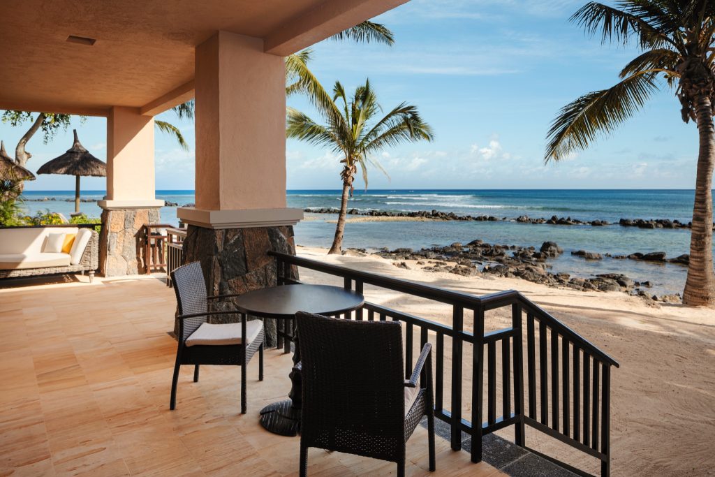 Terrasse der Banyan Suite mit runden Rattantisch, zwei Stühlen, beigen Fliesen und Blick auf das Meer