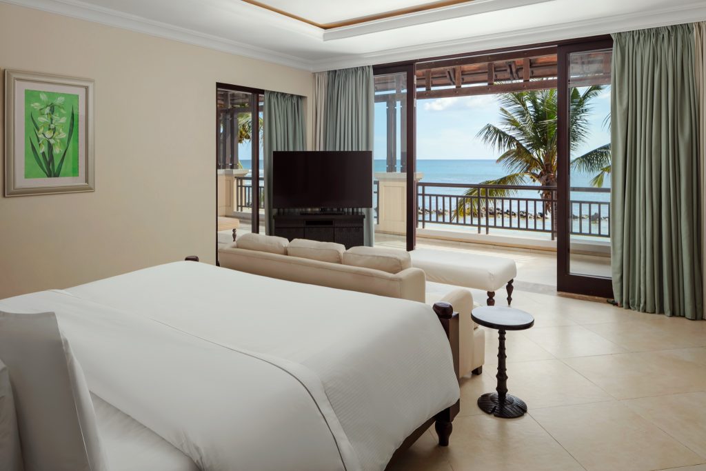 Beachfront Suite Zimmer mit großem Bett, beige Couch, Flachbildfernseher und Balkon mit Meerblick
