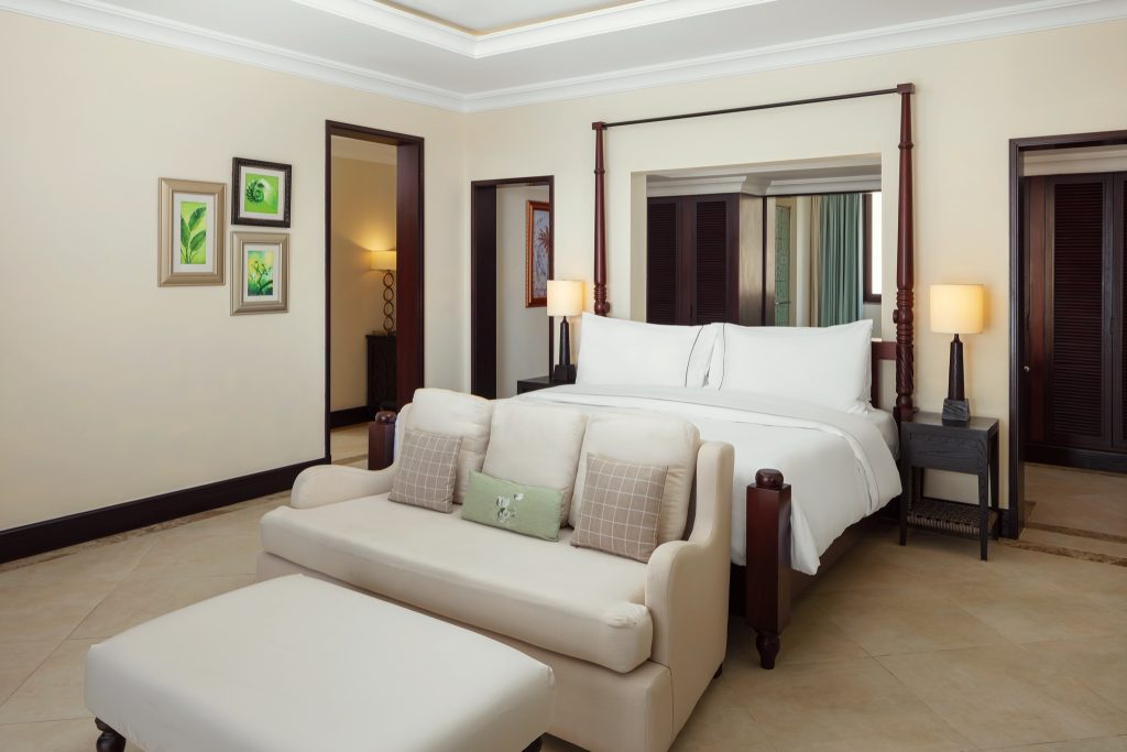 Beachfront Suite Zimmer mit großem Bett, beigem Sofa, Holznachttischen und warmen Beigewänden im The Westin Turtle Bay.