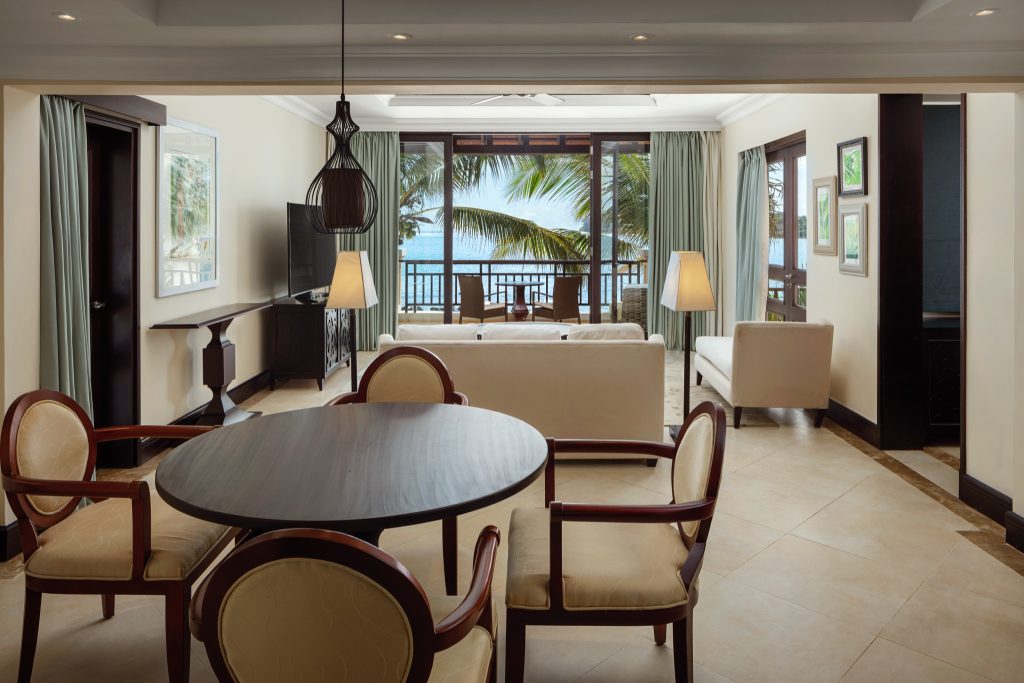 Helles Hotelzimmer mit Wohn- und Essbereich, runder Holztisch, großen Fenstern und Meerblick im The Westin Turtle Bay Resort