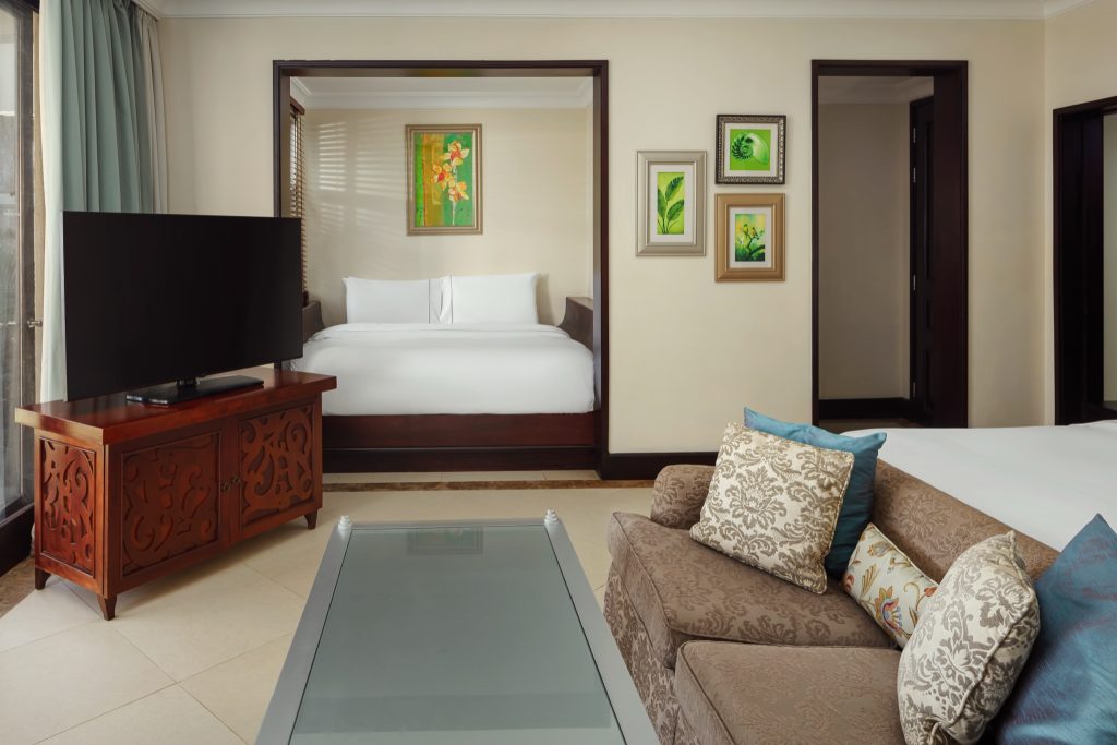 Heavenly Family Junior Suite mit Sofa, Glastisch, Holztisch und großem Bett mit Blumenmalerei