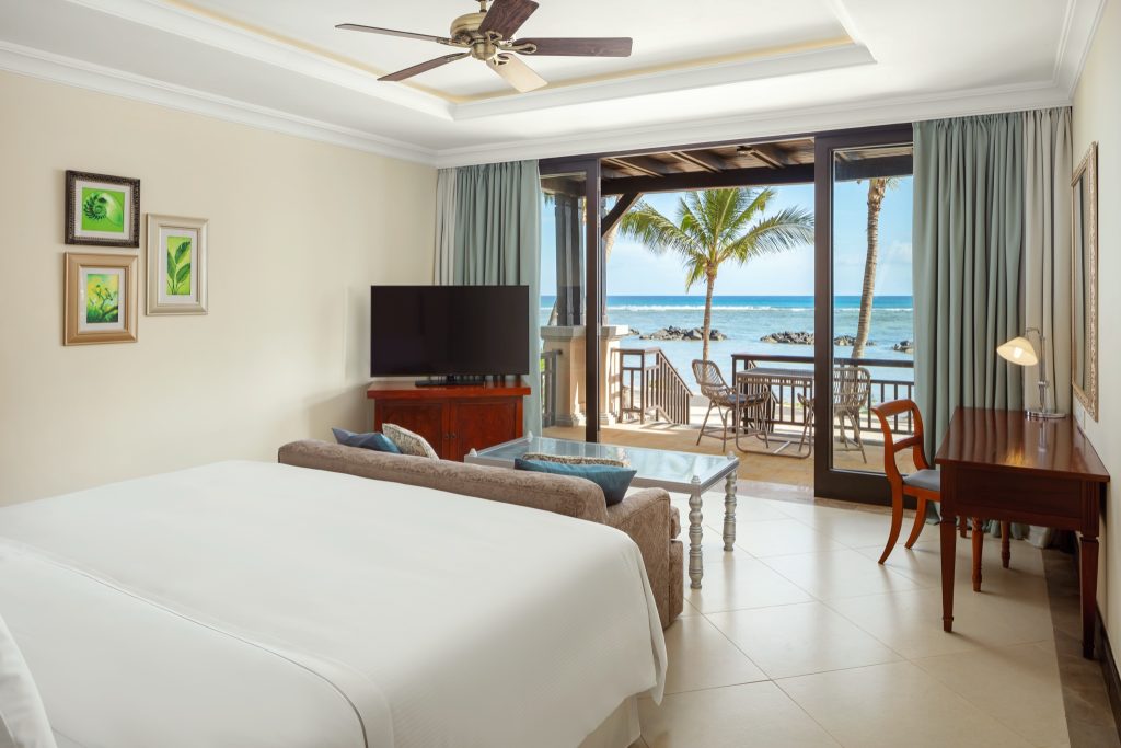 Hell eingerichtetes Zimmer der Heavenly Junior Suite mit großem Bett, Sofa, Meerblick und Terrasse