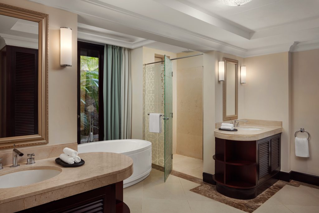 Modernes Badezimmer der Junior Suite mit freistehender Badewanne, dunklen Holzmöbeln und Tageslichtfenster