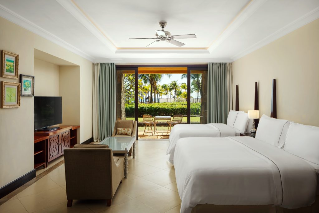 Junior Suite Zimmer mit zwei Betten, Flachbildfernseher, Balkon und Blick auf Palmen in Mauritius