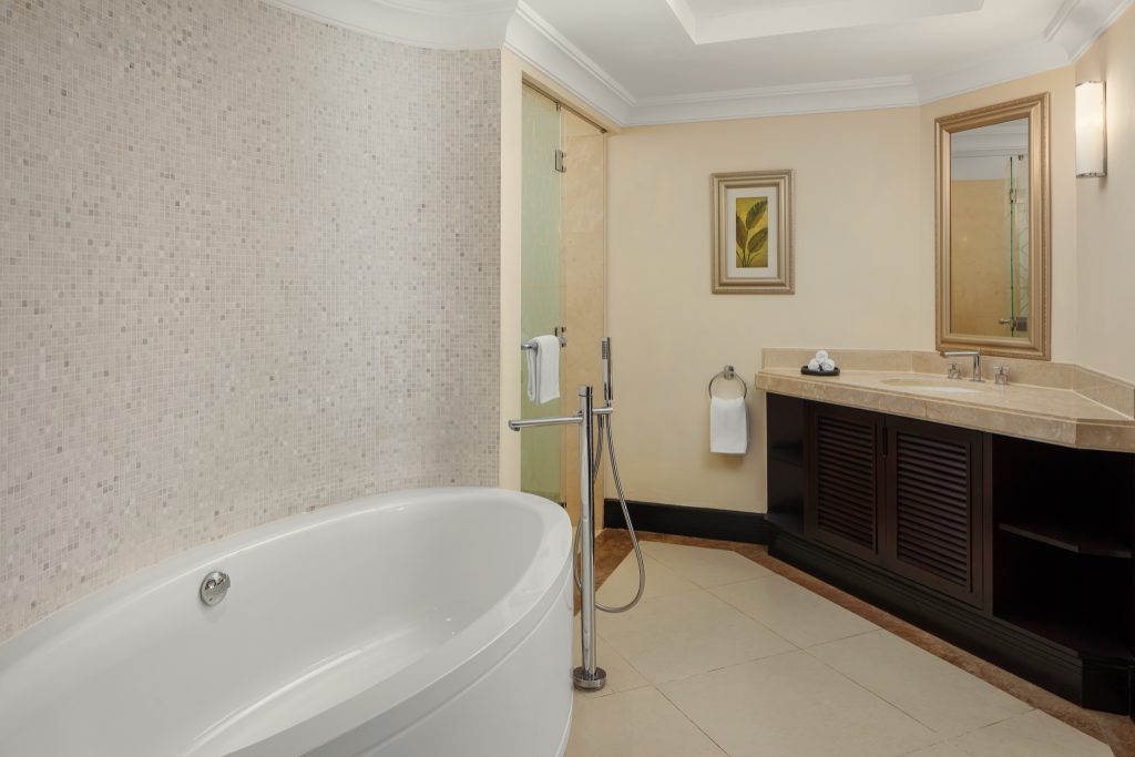 Modernes Badezimmer mit freistehender weißer Badewanne vor Mosaikwand und Waschtisch aus hellem Marmor in Junior Suite