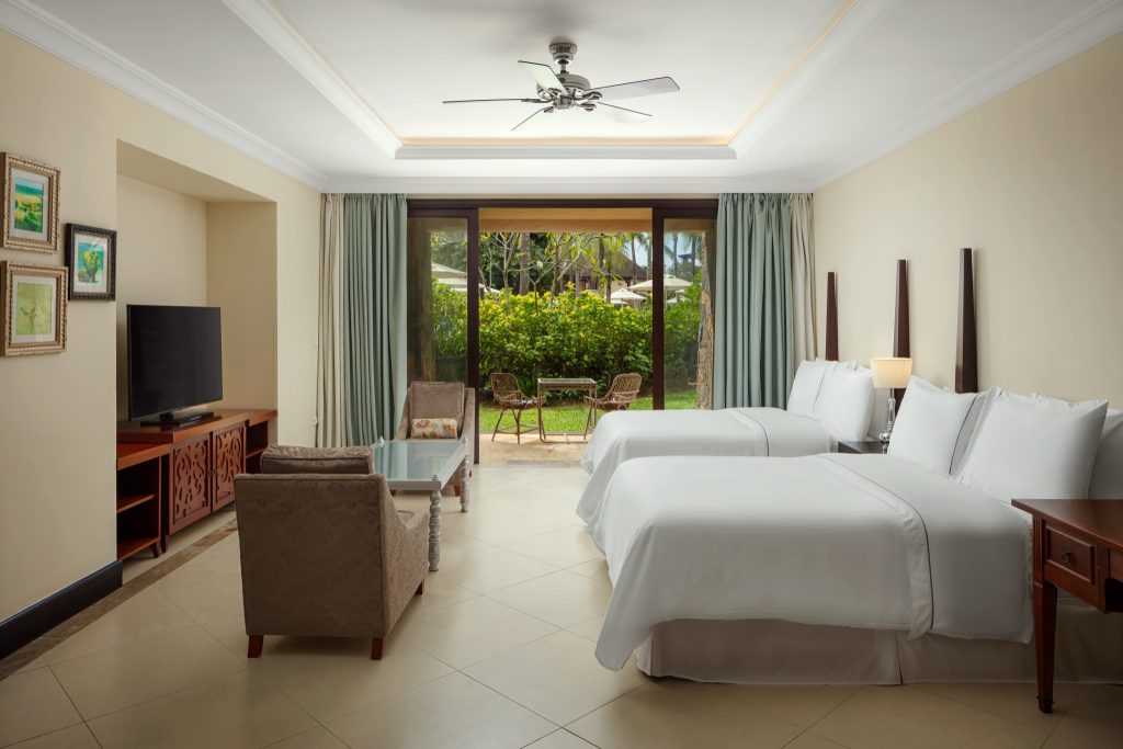 Geräumige Junior Suite mit zwei großen Betten, Sitzecke, Flachbildfernseher und Gartenblick durch Glasschiebetüren