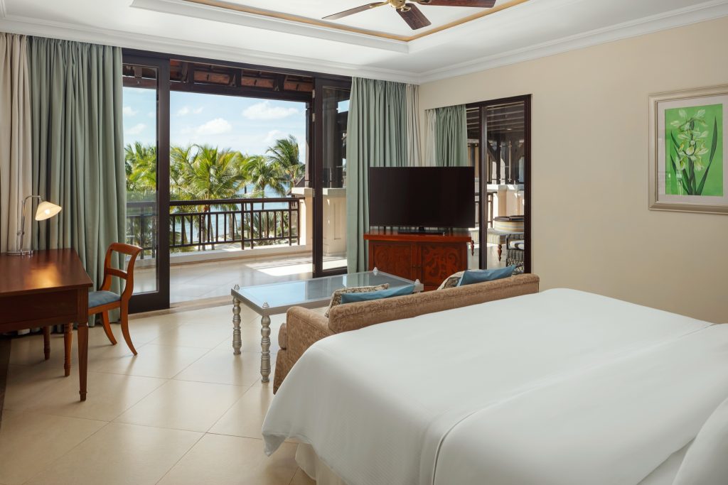 Helles Zimmer der Wellbeing Suite mit großem Bett, Sofa, Schreibtisch und Balkon mit Meerblick