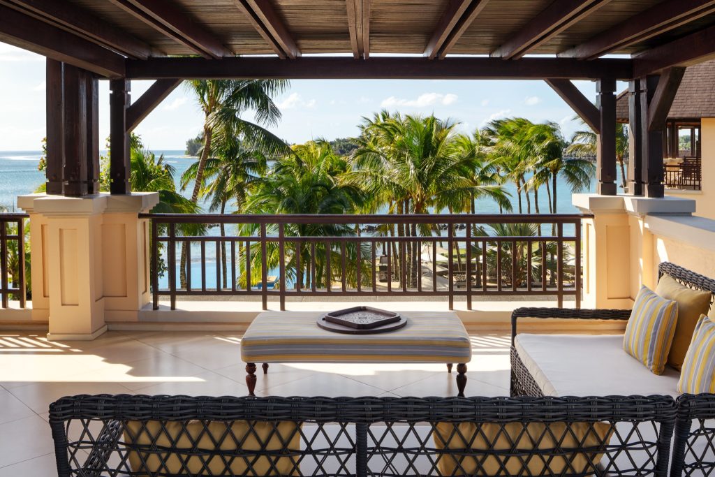 Terrasse der Wellbeing Suite mit Rattanmöbeln, Holzbalustrade und Blick auf Palmen und das Meer