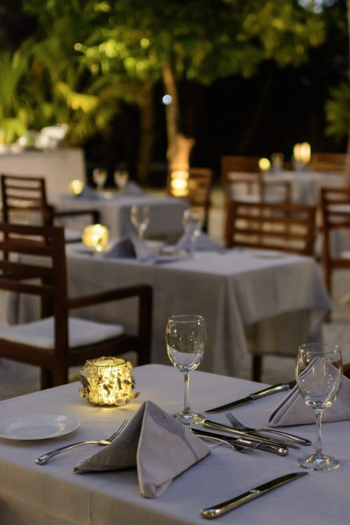Außenbereich des Restaurants diamonds-thudufushi-restaurant-27 mit rechteckigen Tischen, weißen Tischdecken.