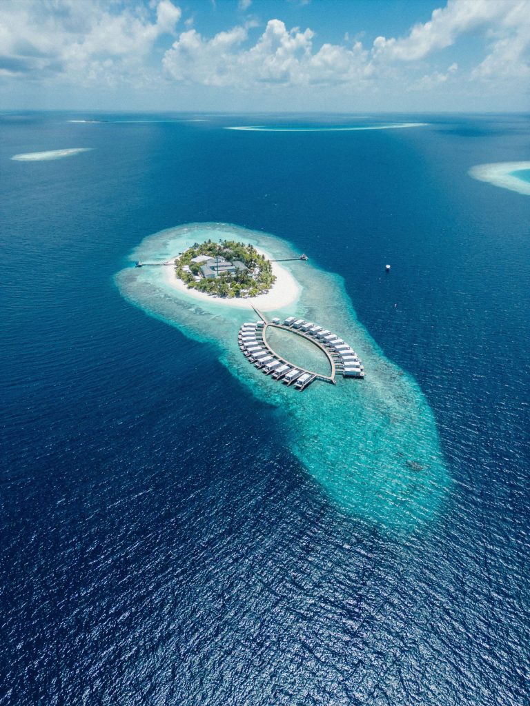 Luftaufnahme der Sandies Bathala Maldives mit Holzbungalows über türkisfarbenem Meer und grünen Palmen auf der Insel