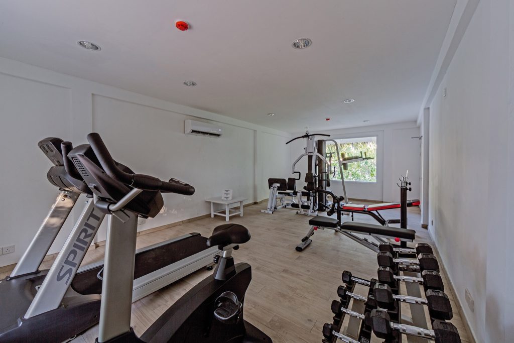 Fitnessraum im Sandies Bathala Maldives mit Laufbändern, Hanteln, Kraftstation und hellen Holzboden