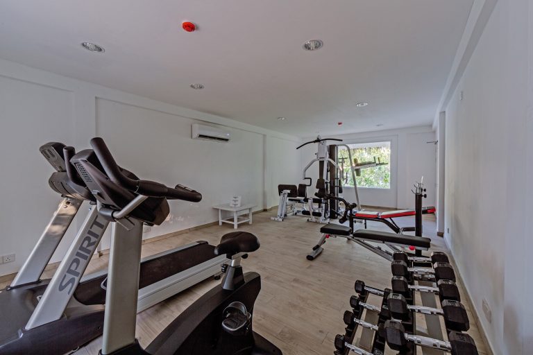 Fitnessraum im Sandies Bathala Maldives mit Laufbändern, Hanteln, Kraftstation und hellen Holzboden