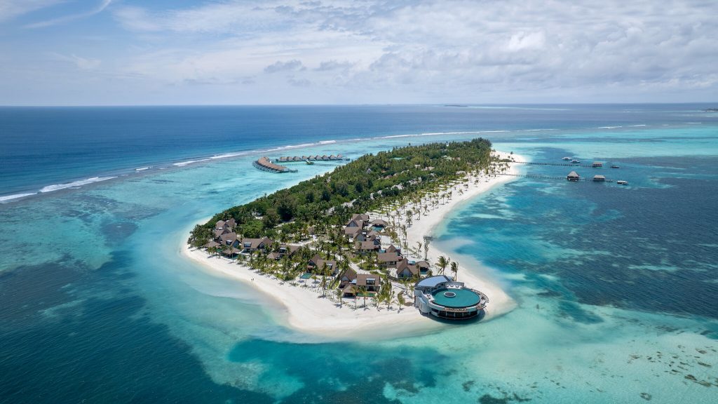 Luftaufnahme von Six Senses Kanuhura mit Strohdachgebäuden, Palmen, hölzernen Stegen und Wasserbungalows auf den