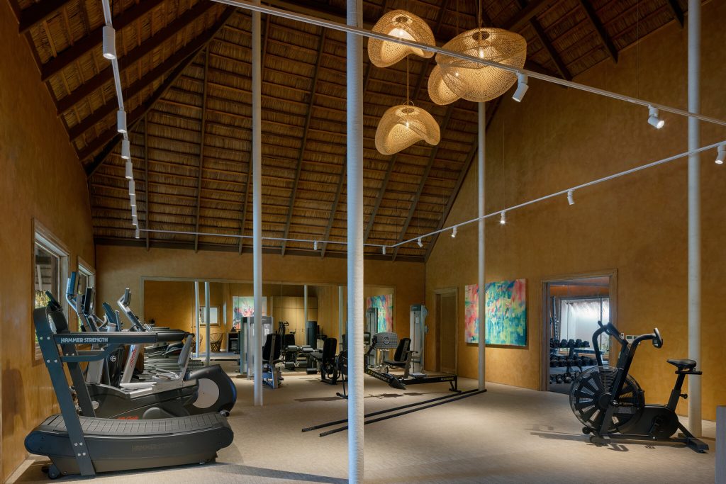 Fitnessraum mit Laufbändern, Fahrradergometer und Kraftgeräten unter hoher