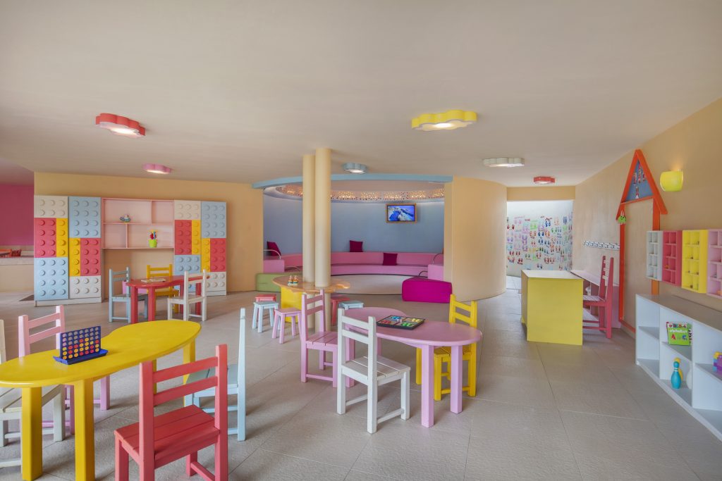 Farbenfroher Spielraum mit kleinen Tischen, Stühlen und Regalen mit runden Noppen in einem Hotel auf Mauritius