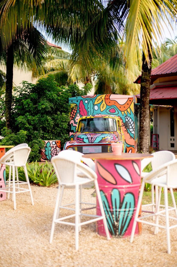 Farbenfroh bemalter Burger Truck im Tamassa Bel Ombre Restaurant mit weißen Barhockern und tropischen Pflanzen