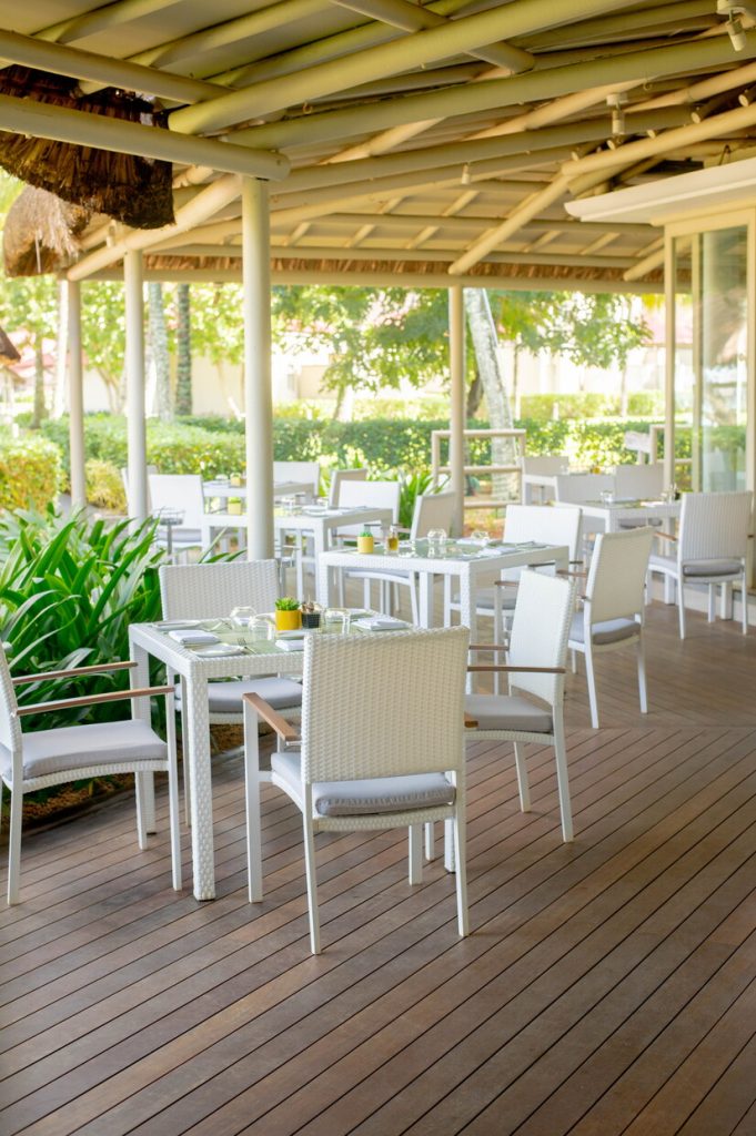 Überdachte Terrasse im Tamassa Bel Ombre restaurant-playa-09 mit weißen Rattan-Tischen und Stühlen auf Holzdeck