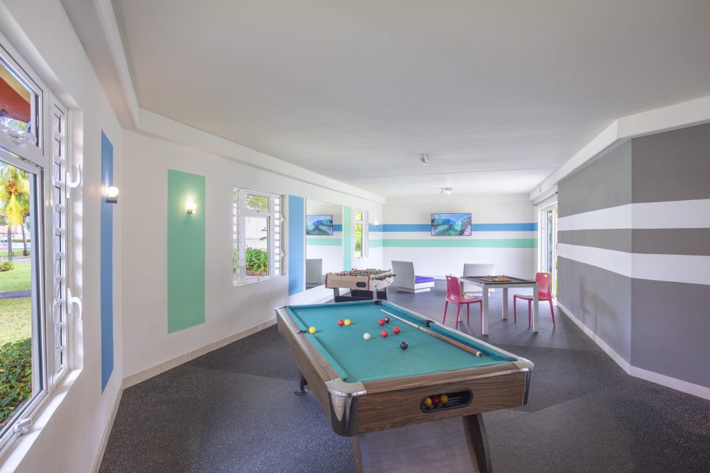 Heller Spieleraum mit Billardtisch, Tischkicker und Sitzbereich mit Tisch und Stühlen in Tamassa Bel Ombre