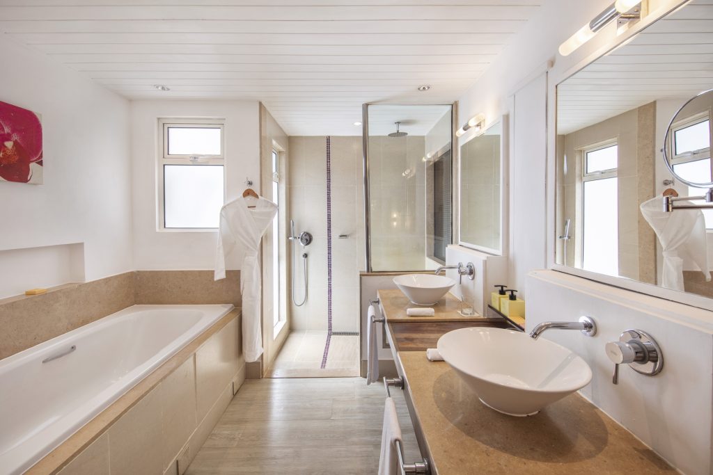 Badezimmer im Beach Room des Tamassa Bel Ombre mit Doppelwaschbecken, Badewanne, Dusche