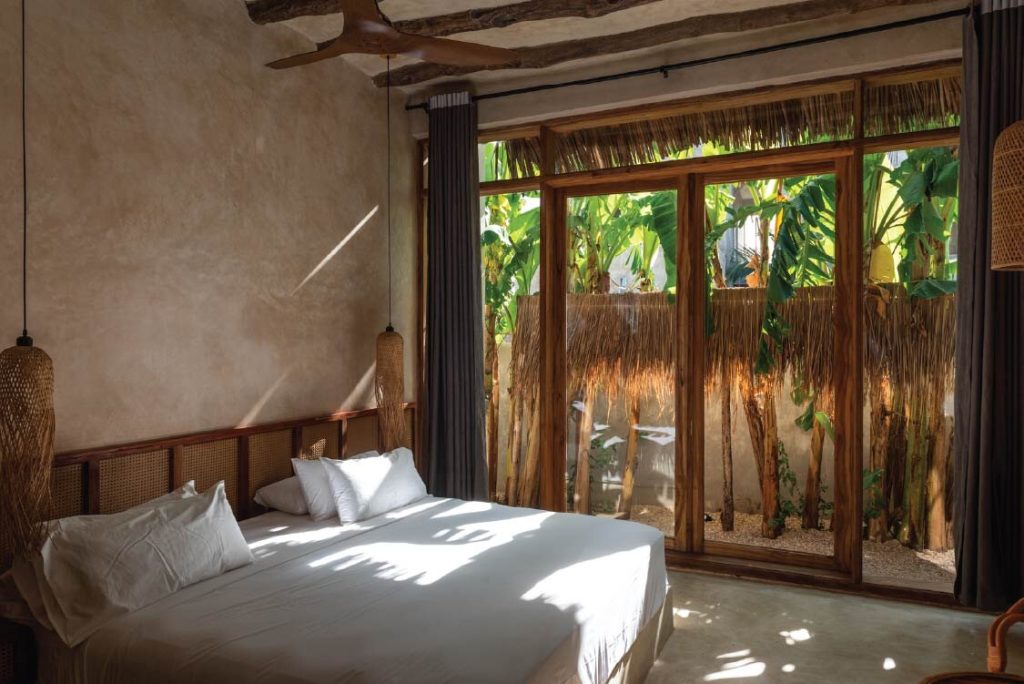 Hotelzimmer Stone Town Double mit großem Bett, weißen Bettwäsche und Holzfenstern mit Blick auf Garten