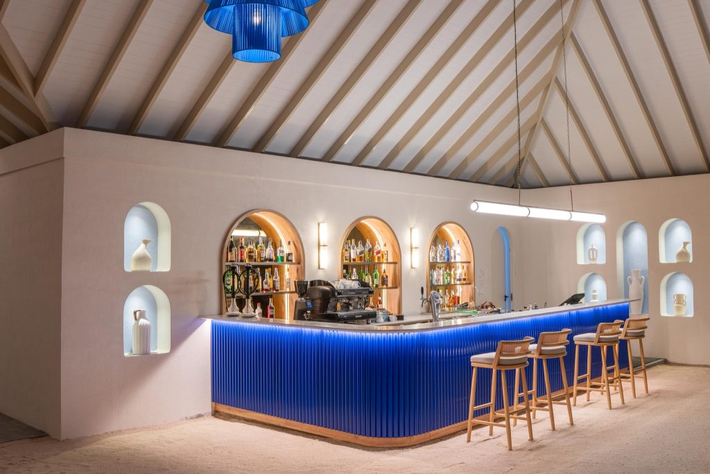 Frontalaufnahme der Bar Sip Dip im Eri Maldives mit blauem Tresen, hölzernen Barhockern und dekorativen Vasen