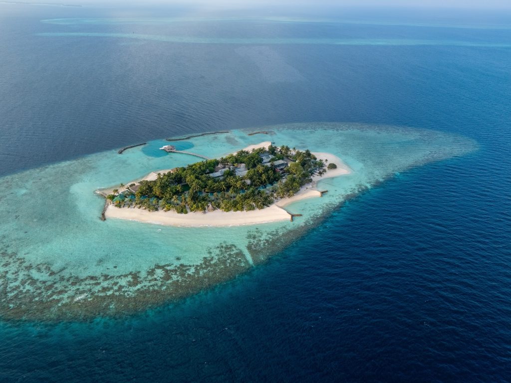 Luftaufnahme der Eri Maldives Insel mit weißem Sandstrand, Palmen und Holzgebäuden inmitten blauem Meer