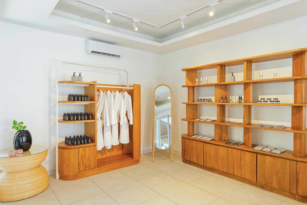 Verkaufsraum im Eri Maldives Wellness Eskape Spa mit Holzschrank, weißen Bademänteln und Spiegel