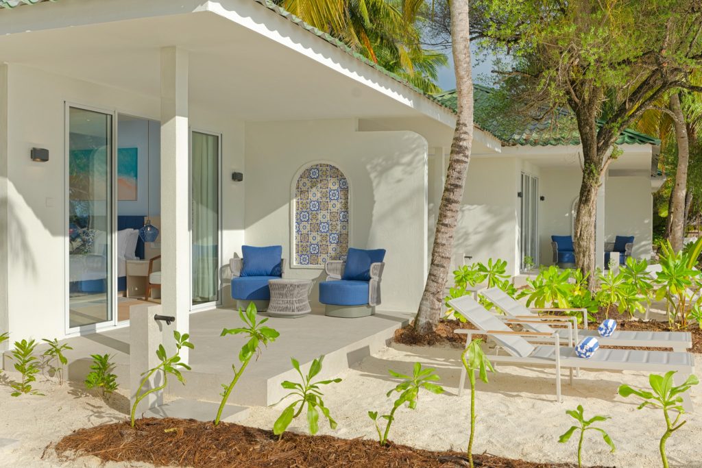 Terrasse der Beach Villa im Eri Maldives mit zwei blauen Sesseln, kleinem Tisch und weißen Liegestühlen am Sand
