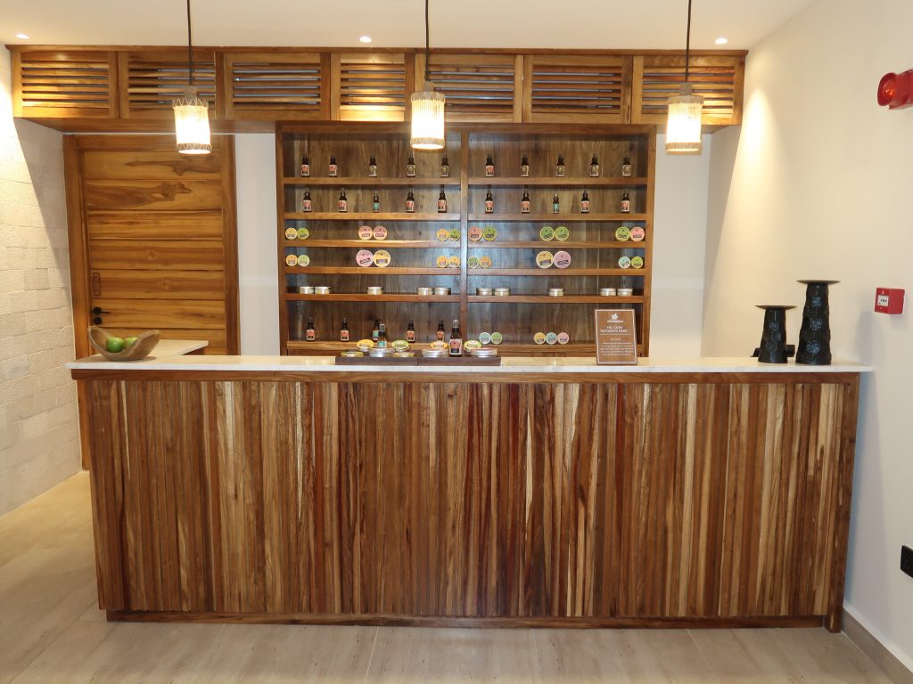 Empfangsbereich der Jaz Amaluna Bar mit mitteldunklem Holztheken und Regal mit Flaschen