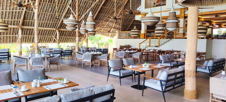 Offenes Restaurant Amani im Jaz Amaluna mit Stroh-Dach, Holz- und Stoffmöbeln in Grau- und Beigetönen und geflochtenen Lampen