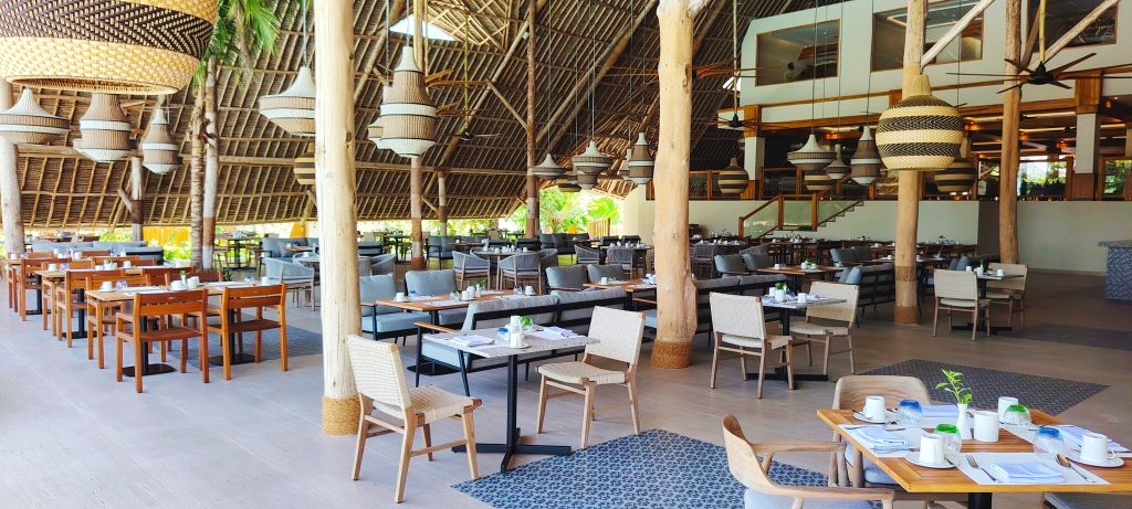 Geräumiges Restaurant Amani im Jaz Amaluna mit hohem schrägem Dach, Holztischen und gewebten Lampenschirmen