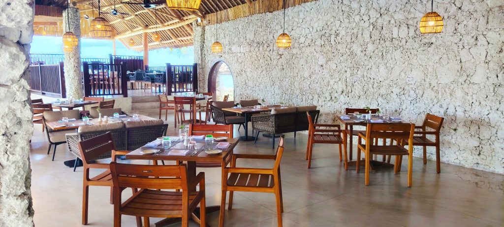 Offener Restaurantbereich Mareya Beach im Jaz Amaluna mit Holztischen, Natursteinwänden